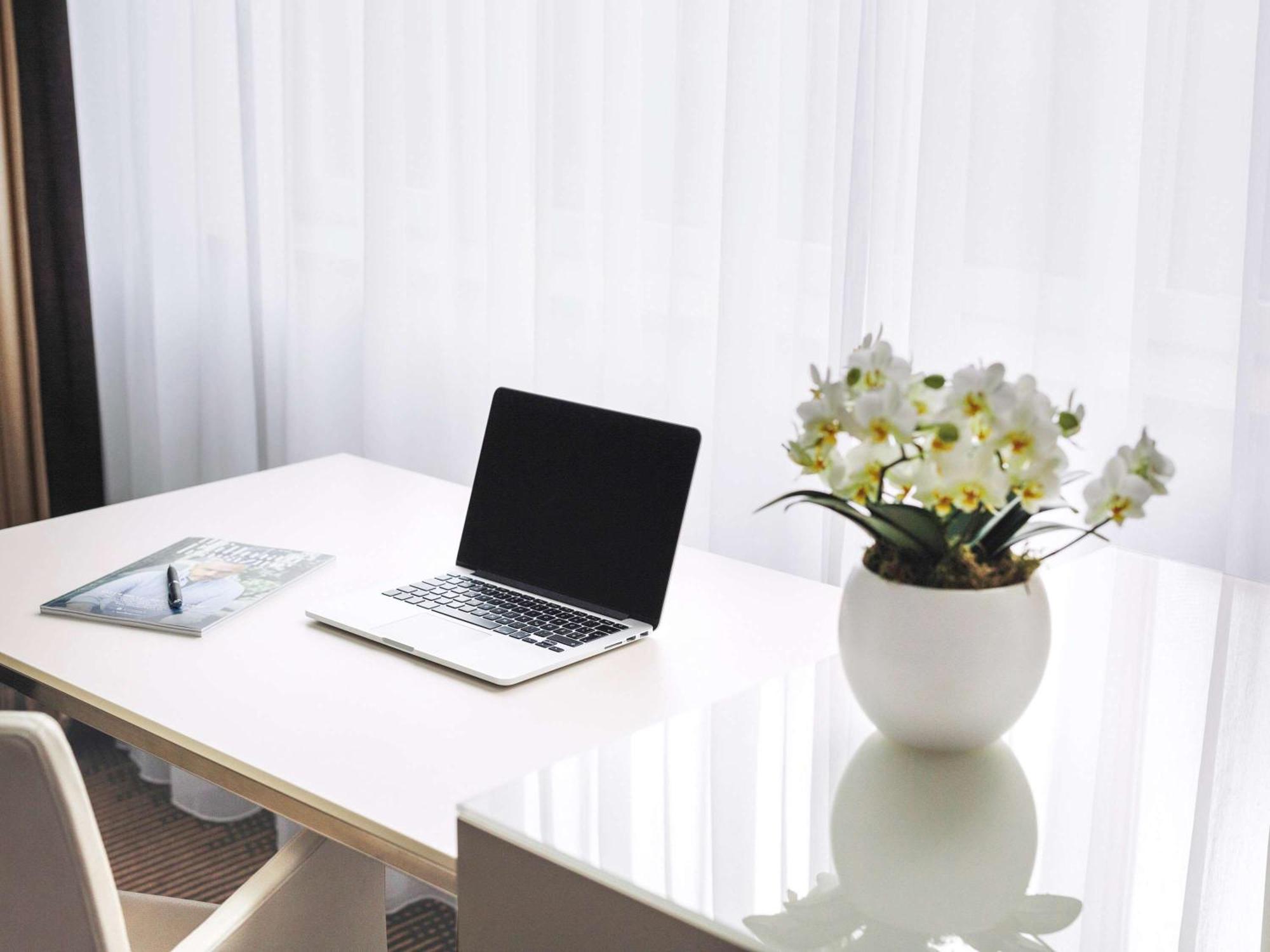 Hotel Pullman Berlin Schweizerhof Esterno foto A desk with a laptop and a vase of flowers